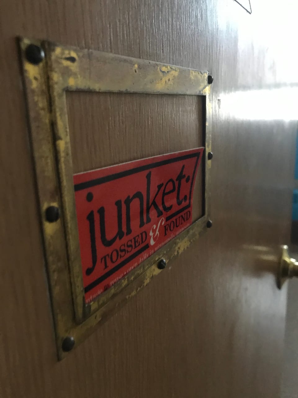 Photo caption: close-up of an office door with a junket logo sticker tucked into the nameplate holder.